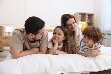 Photo of Happy family wearing pajamas on bed at home