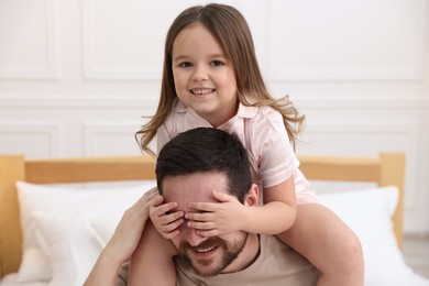 Photo of Happy father with his daughter wearing pajamas at home