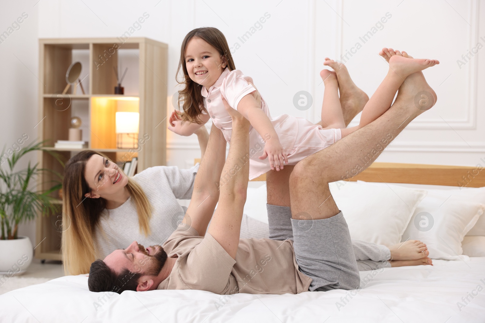 Photo of Happy family wearing pajamas having fun on bed at home