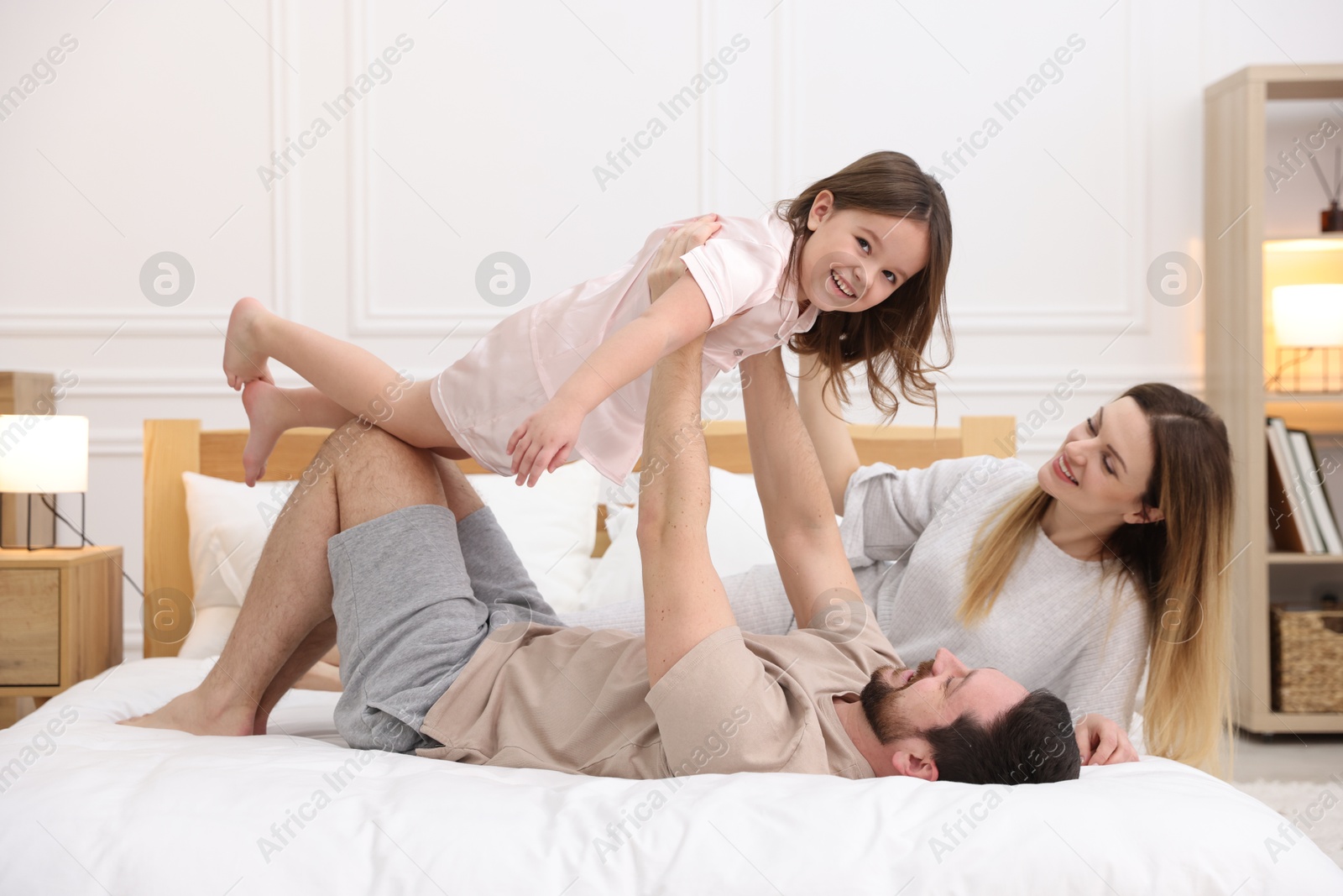 Photo of Happy family wearing pajamas having fun on bed at home