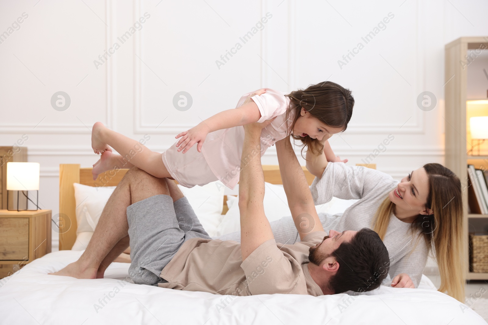 Photo of Happy family wearing pajamas having fun on bed at home