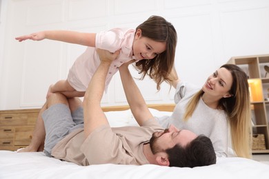 Photo of Happy family wearing pajamas having fun on bed at home