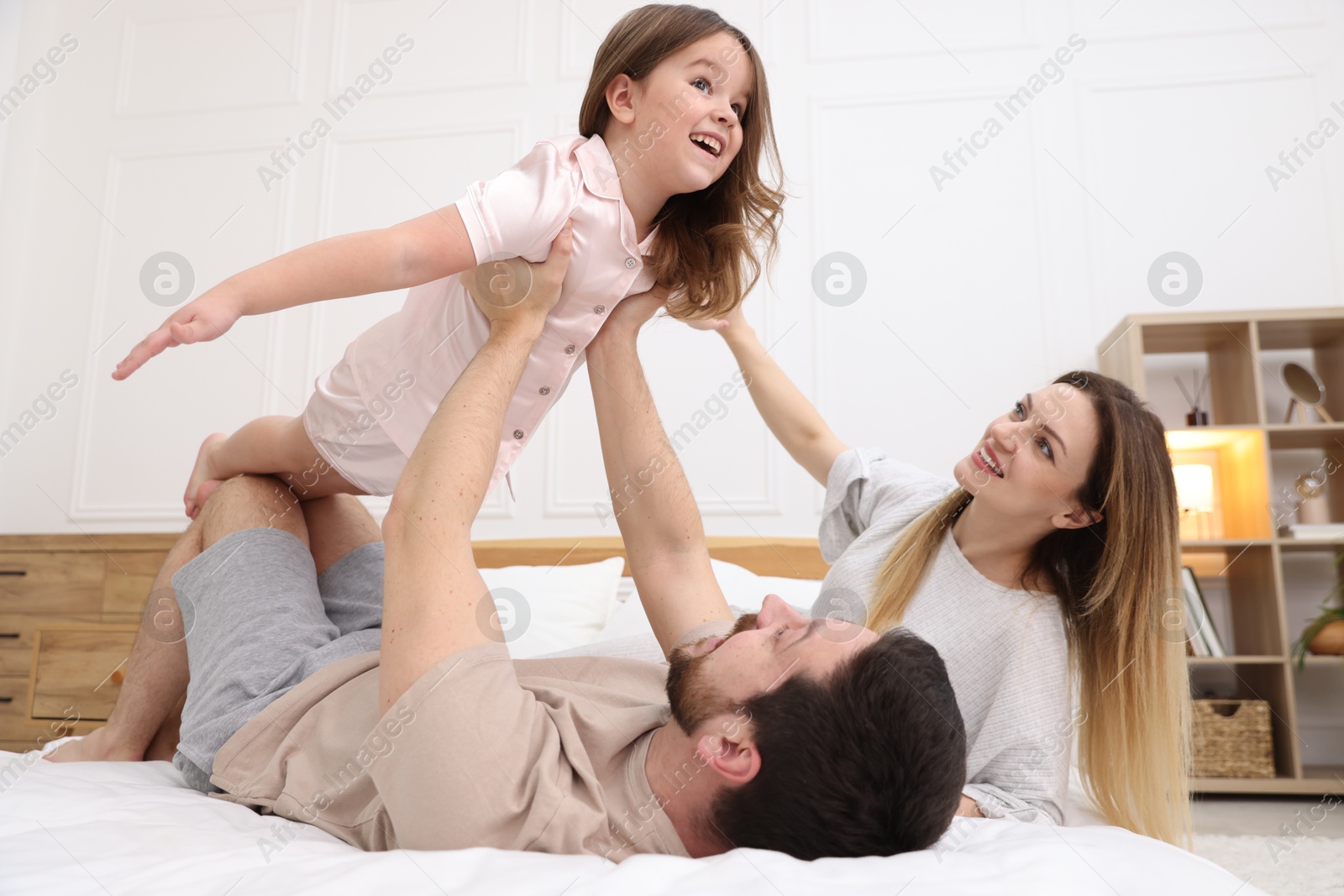 Photo of Happy family wearing pajamas having fun on bed at home