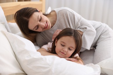 Photo of Happy mother and her daughter wearing pajamas on bed at home