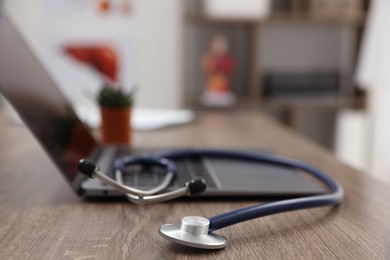 Photo of Laptop and stethoscope on desk in medical office, closeup. Space for text