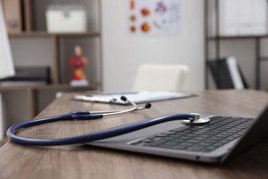 Photo of Laptop and stethoscope on desk in medical office, closeup. Space for text