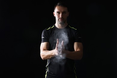 Photo of Man clapping hands with talcum powder before training on black background