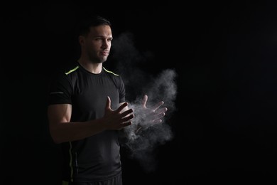 Photo of Man clapping hands with talcum powder before training on black background. Space for text