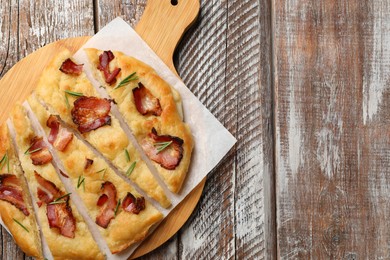 Photo of Slices of delicious focaccia bread with bacon and rosemary on wooden table, top view. Space for text