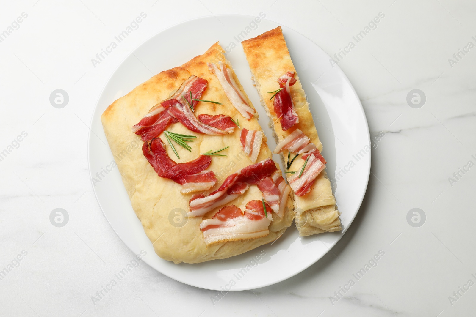 Photo of Pieces of delicious focaccia bread with bacon and rosemary on white marble table, top view