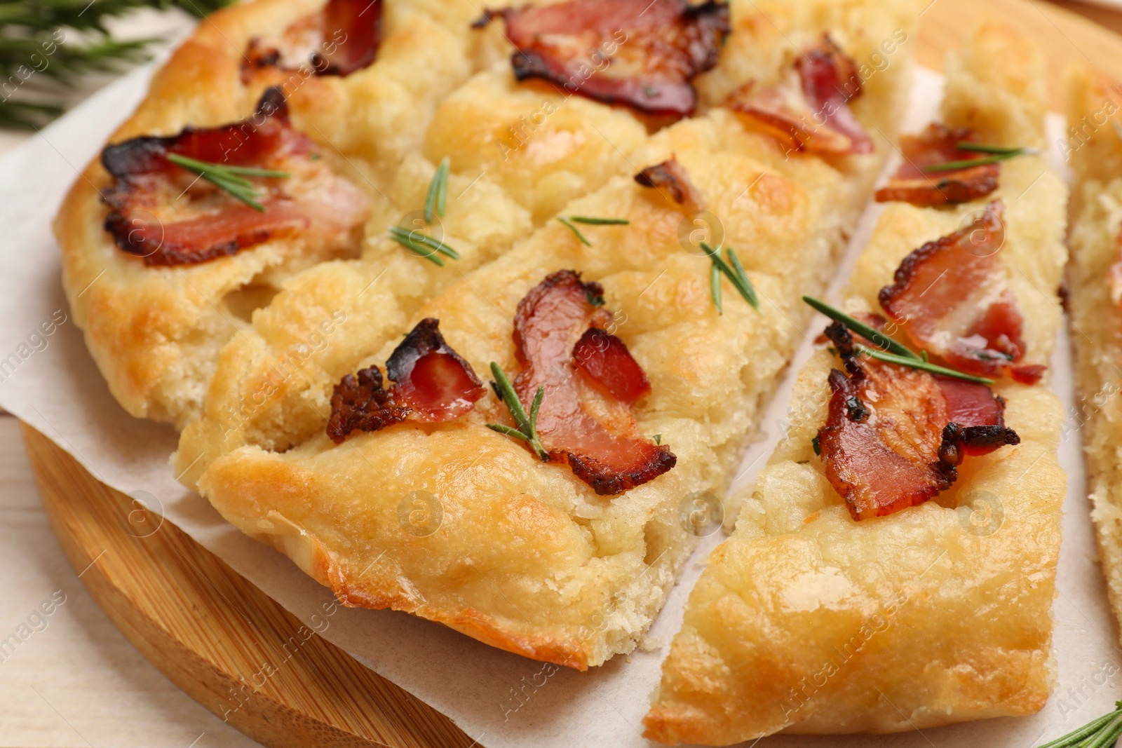 Photo of Slices of delicious focaccia bread with bacon and rosemary on table, closeup