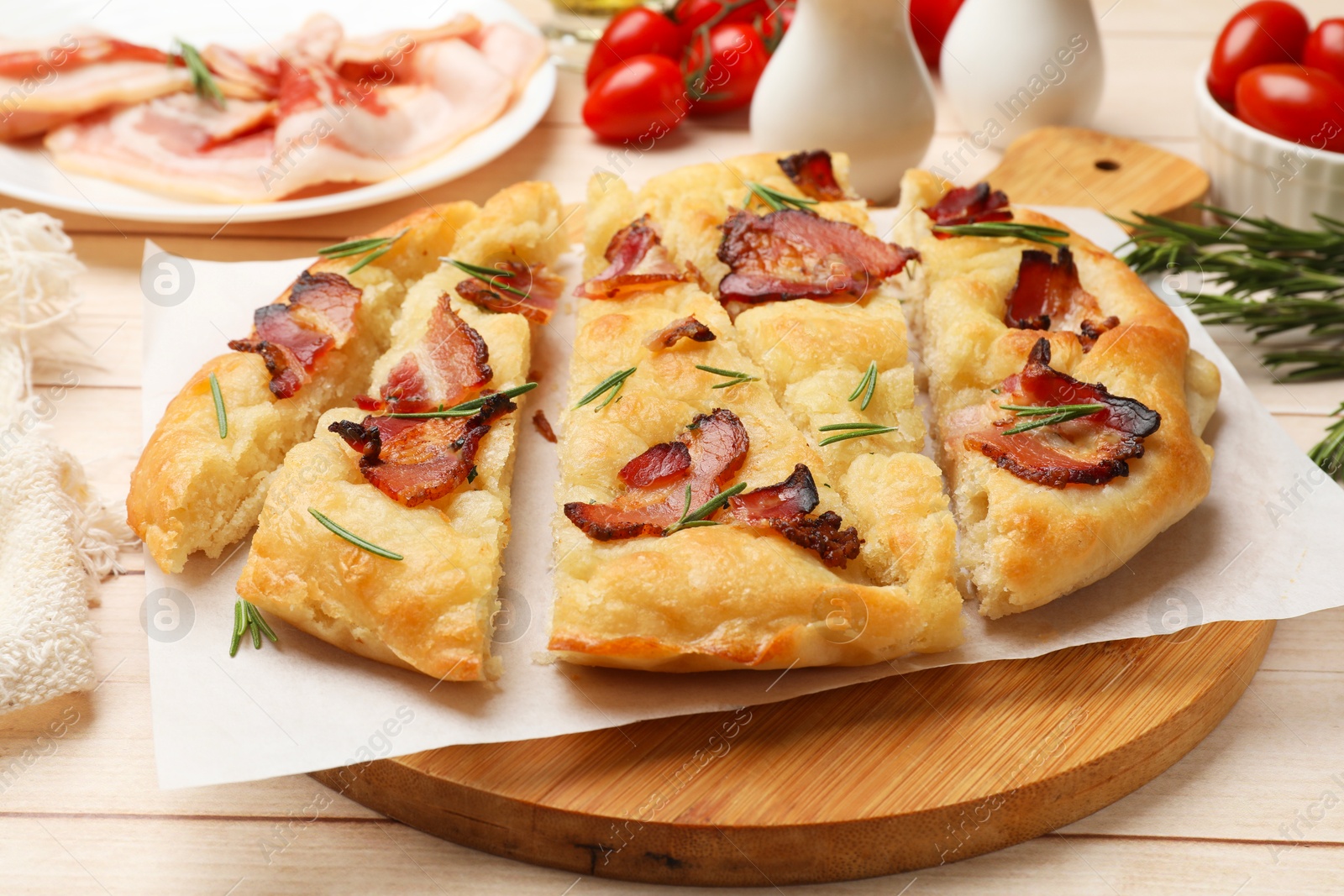 Photo of Slices of delicious focaccia bread with bacon and rosemary on wooden table, closeup