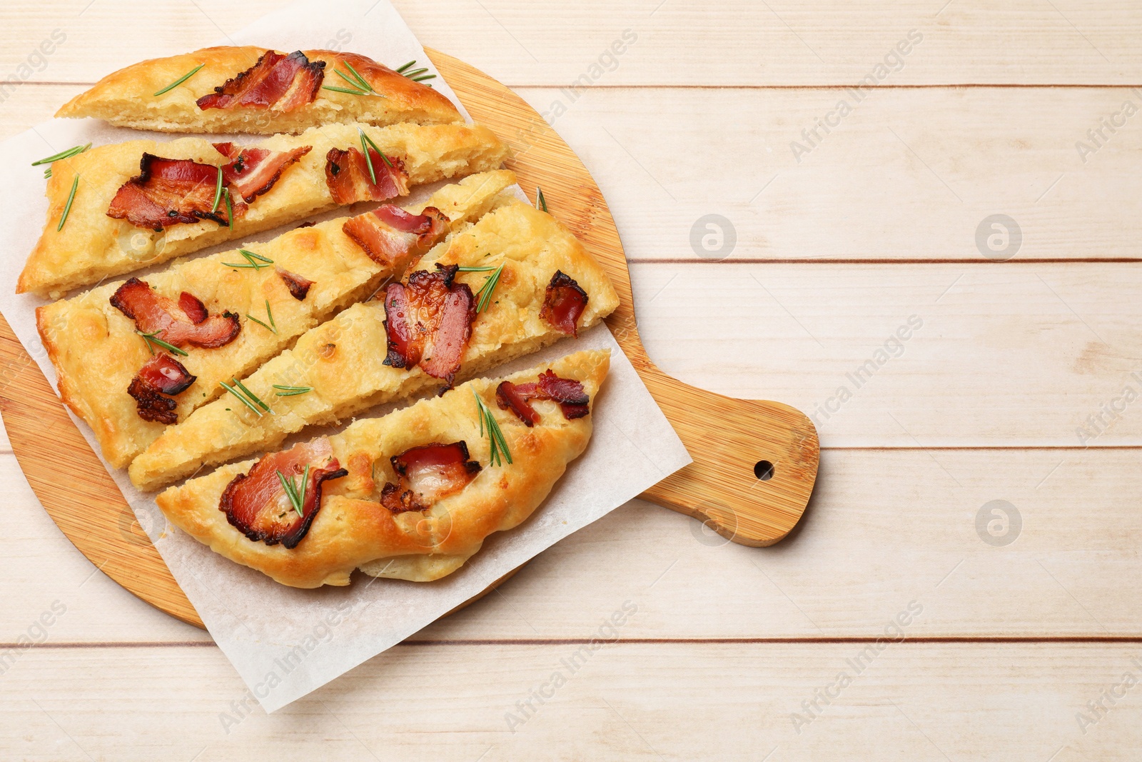 Photo of Slices of delicious focaccia bread with bacon and rosemary on wooden table, top view. Space for text