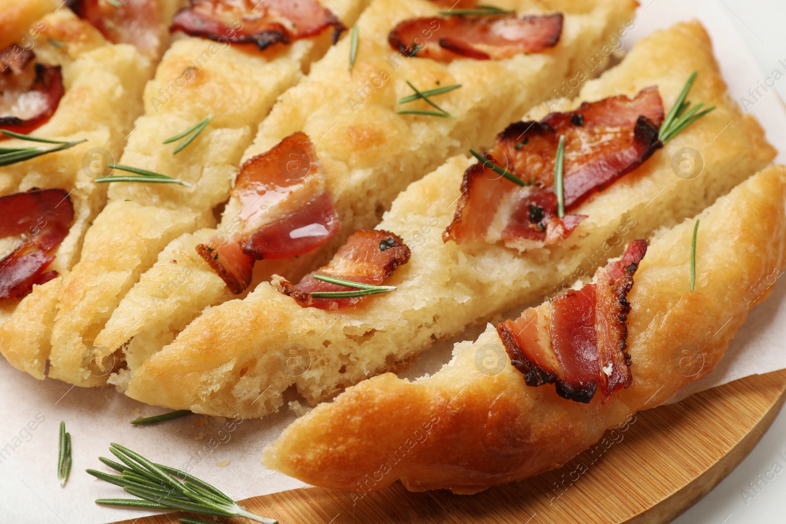 Photo of Slices of delicious focaccia bread with bacon and rosemary on table, closeup