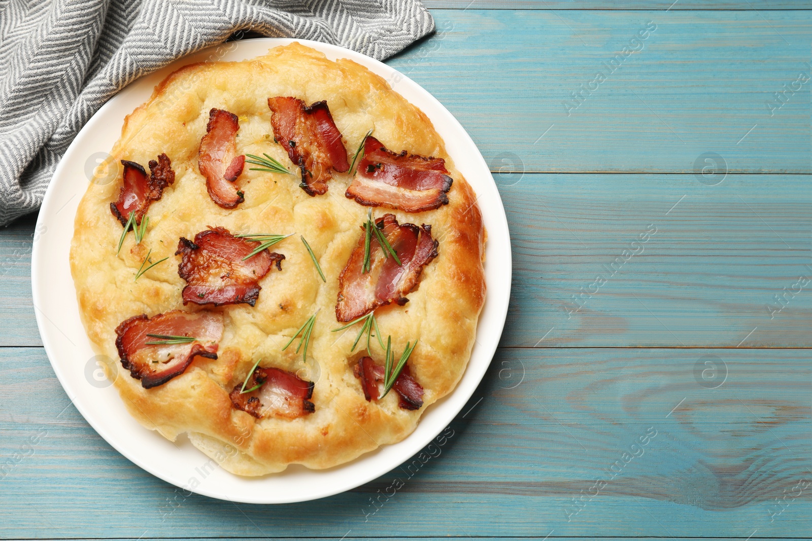 Photo of Delicious focaccia bread with bacon and rosemary on light blue wooden table, top view. Space for text