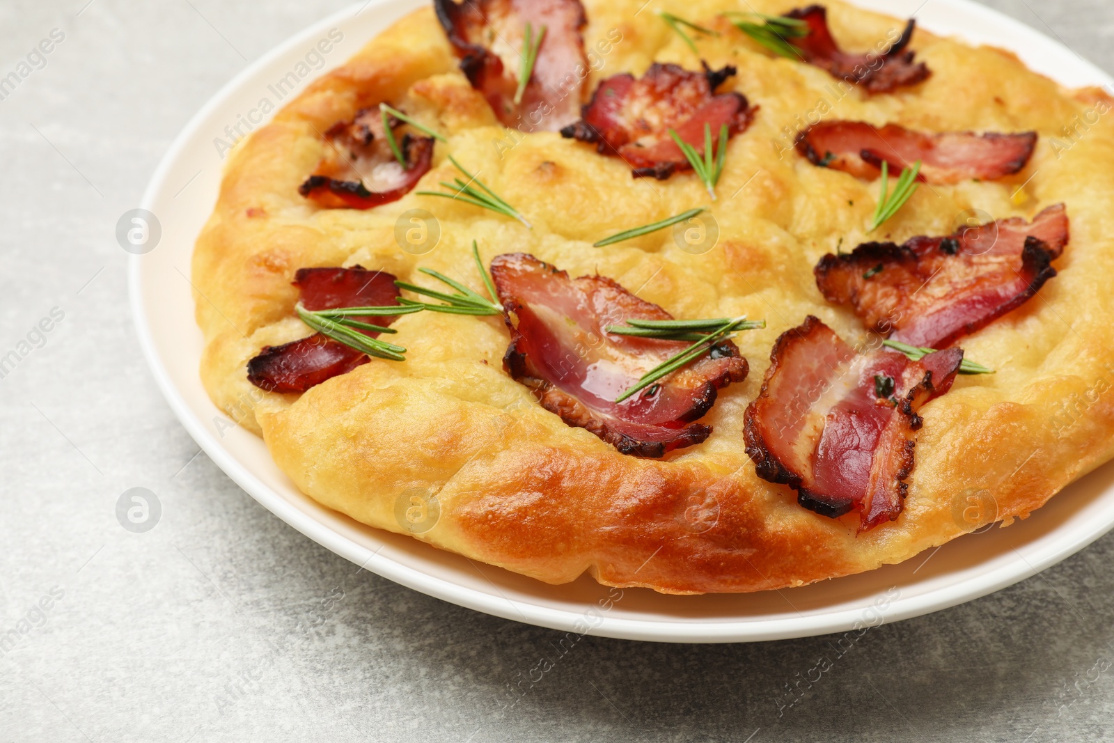 Photo of Delicious focaccia bread with bacon and parsley on light grey table, closeup