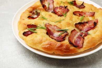 Photo of Delicious focaccia bread with bacon and parsley on light grey table, closeup