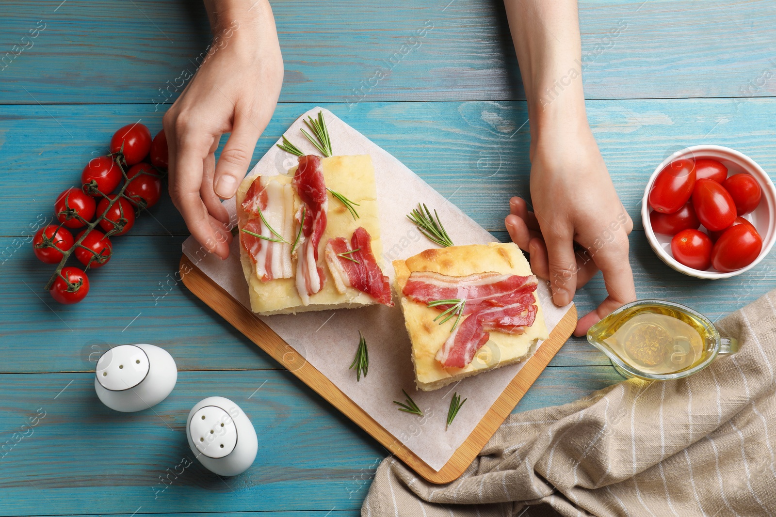 Photo of Woman serving delicious focaccia bread at blue wooden table, top view