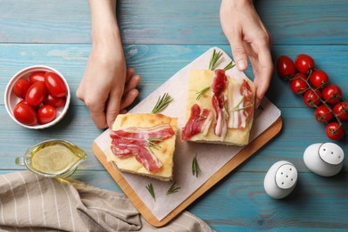 Photo of Woman serving delicious focaccia bread at blue wooden table, top view