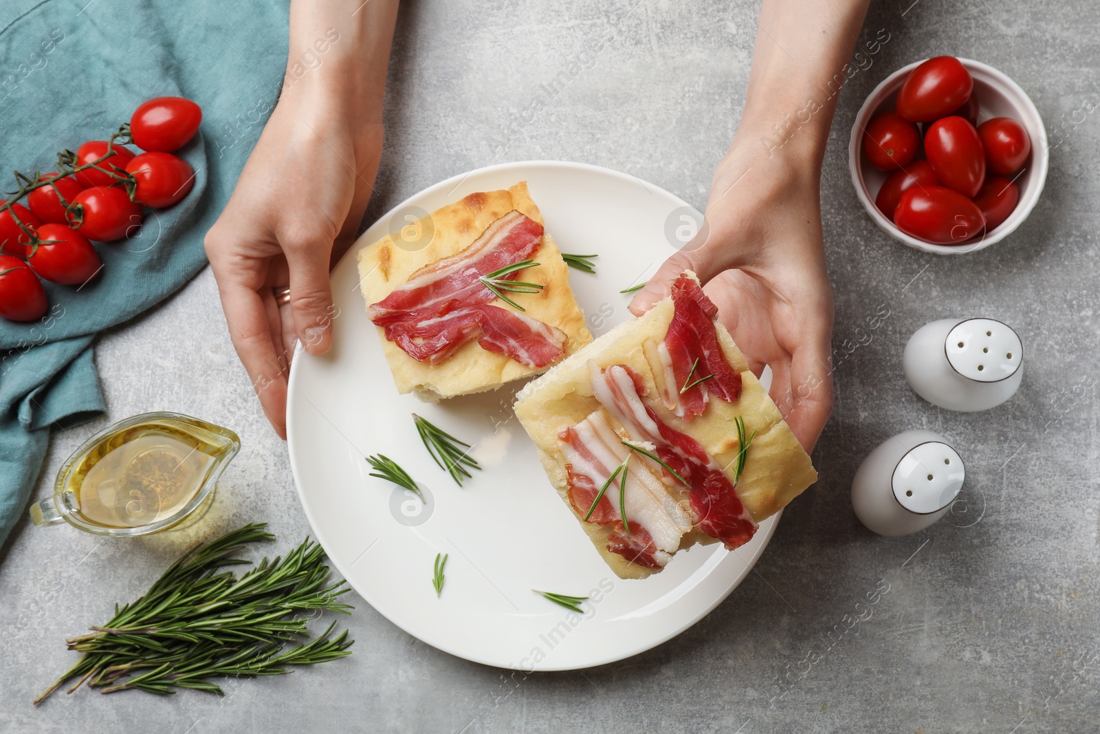 Photo of Woman serving delicious focaccia bread at grey table, top view