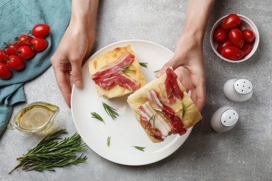 Photo of Woman serving delicious focaccia bread at grey table, top view