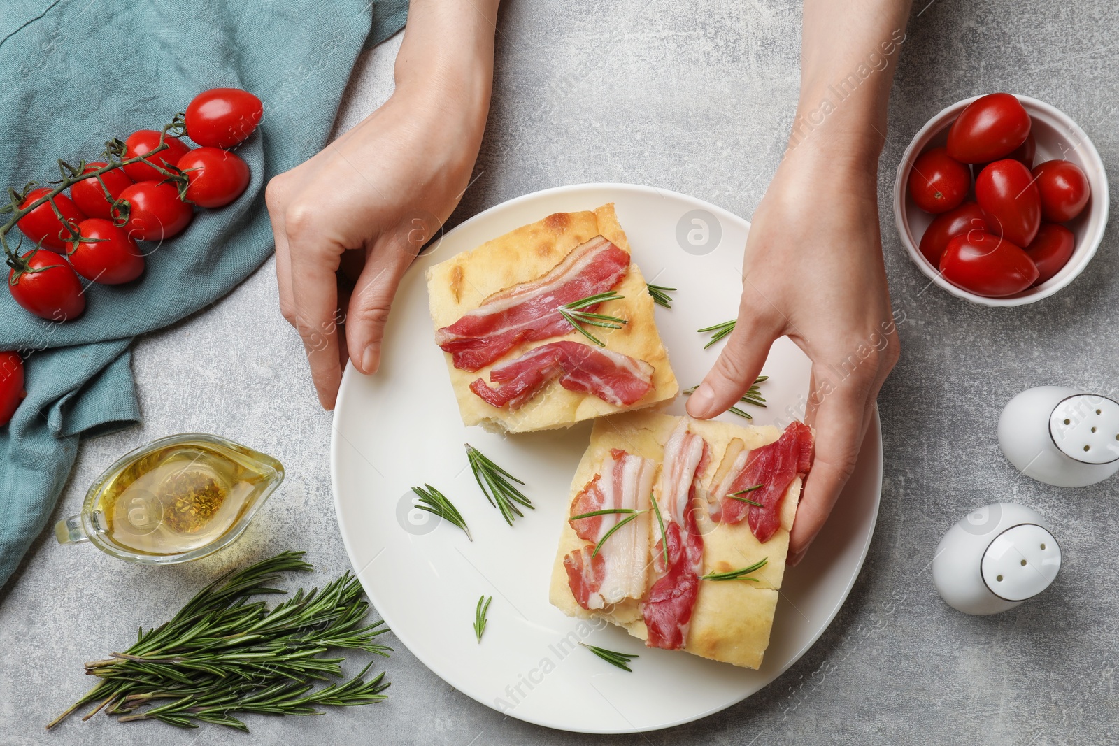 Photo of Woman serving delicious focaccia bread at grey table, top view