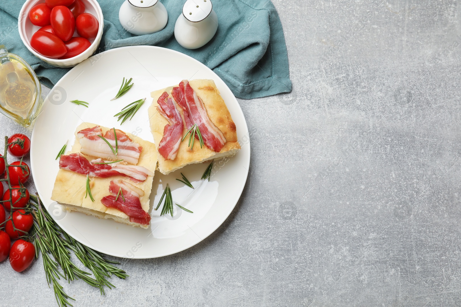 Photo of Pieces of delicious focaccia bread with bacon served on grey table, flat lay. Space for text