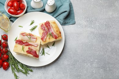 Photo of Pieces of delicious focaccia bread with bacon served on grey table, flat lay. Space for text