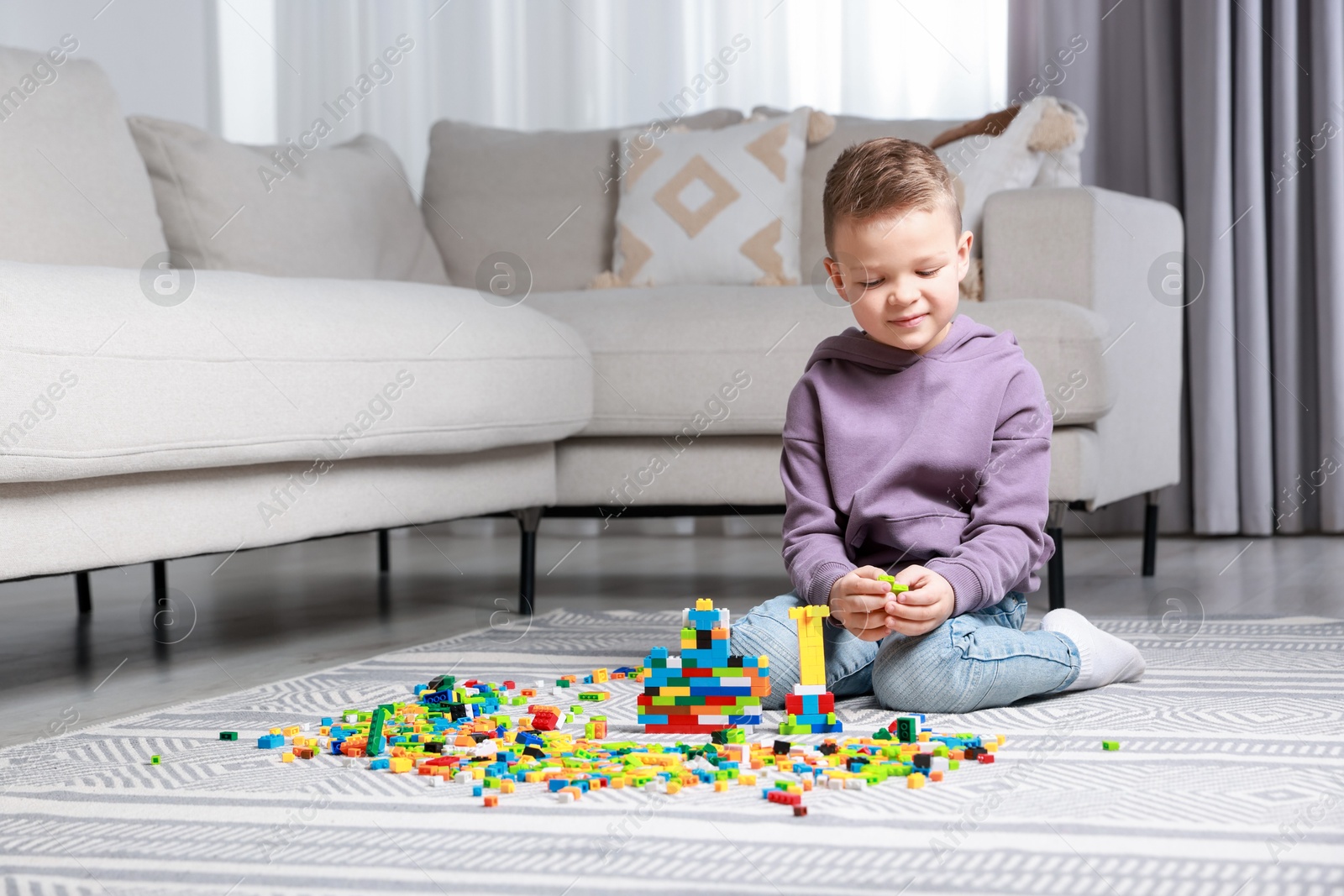 Photo of Cute boy playing with building blocks on floor at home. Space for text