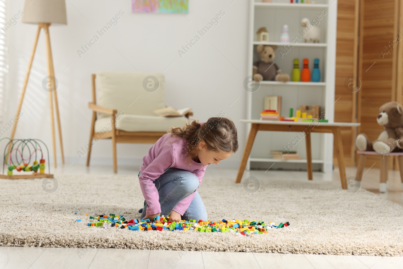 Photo of Cute girl playing with building blocks on floor at home