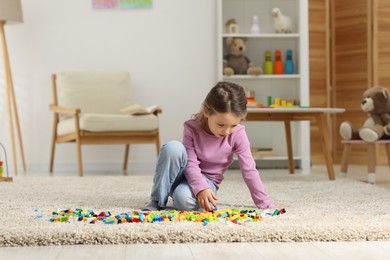 Photo of Cute girl playing with building blocks on floor at home