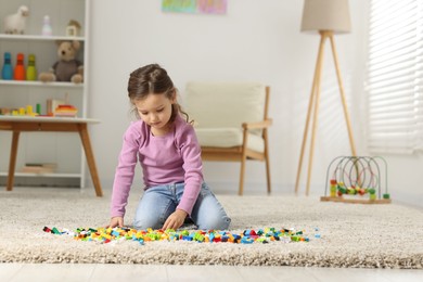 Photo of Cute girl playing with building blocks on floor at home