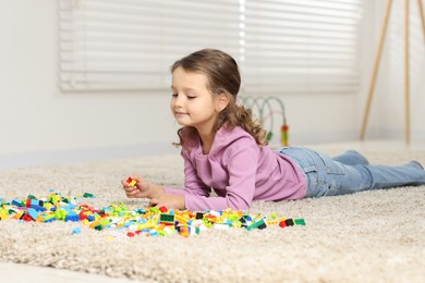 Photo of Cute girl playing with building blocks on floor at home