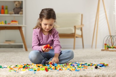 Photo of Cute girl playing with building blocks on floor at home