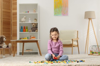 Photo of Cute girl playing with building blocks on floor at home