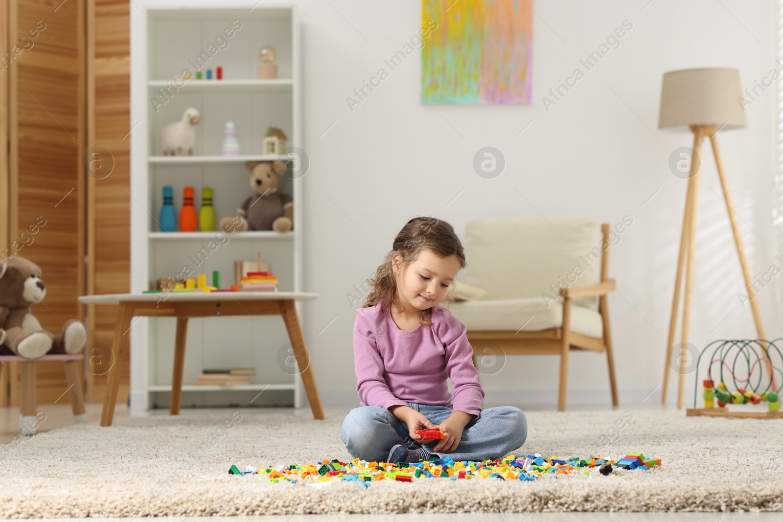 Photo of Cute girl playing with building blocks on floor at home