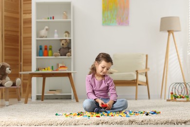 Photo of Cute girl playing with building blocks on floor at home