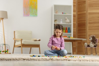 Photo of Cute girl playing with building blocks on floor at home. Space for text