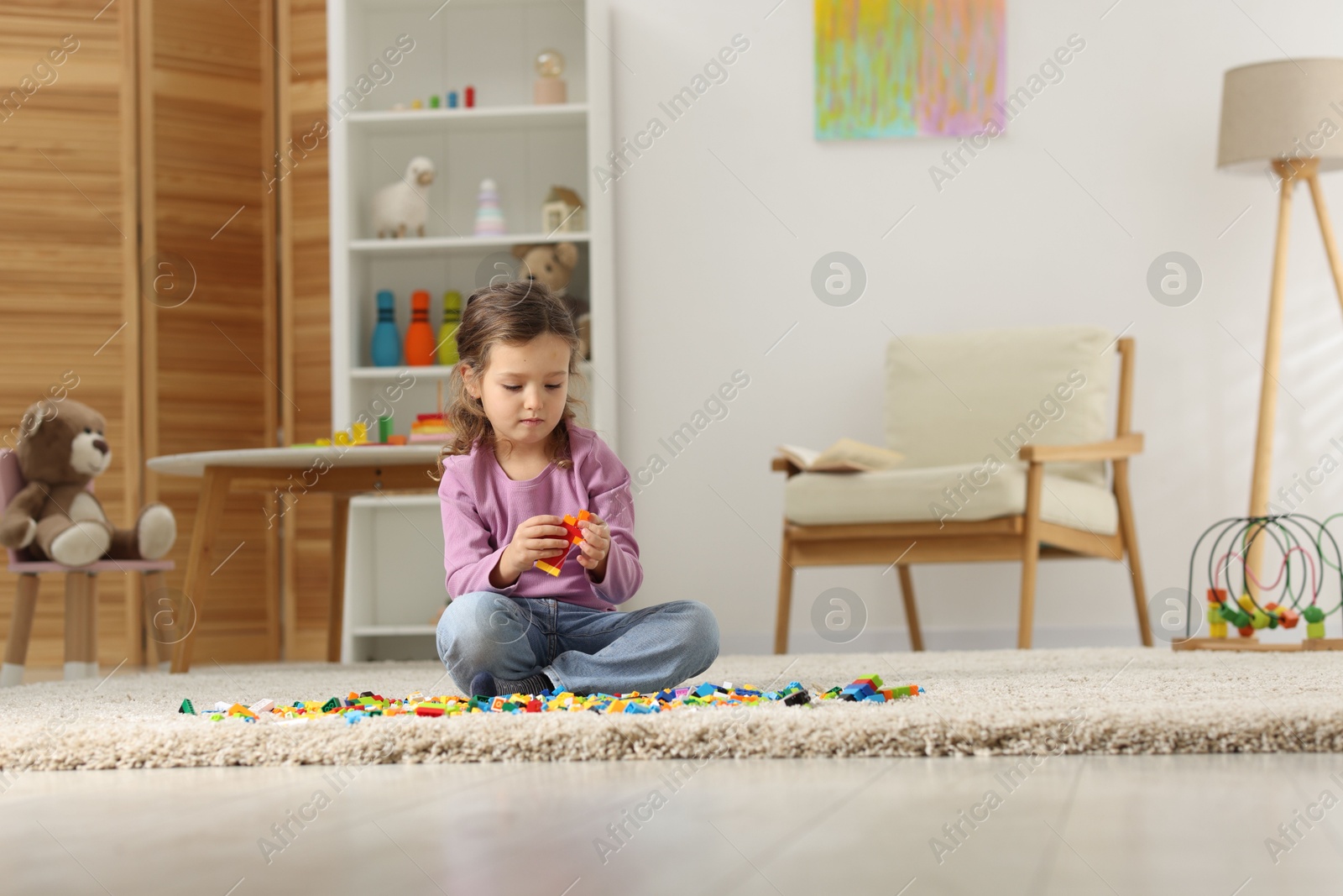 Photo of Cute girl playing with building blocks on floor at home. Space for text