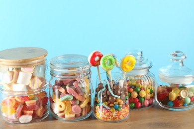 Photo of Candy bar. Many different sweets on wooden table against light blue background, closeup. Space for text