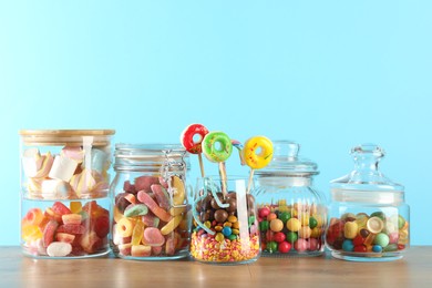 Candy bar. Many different sweets on wooden table against light blue background. Space for text