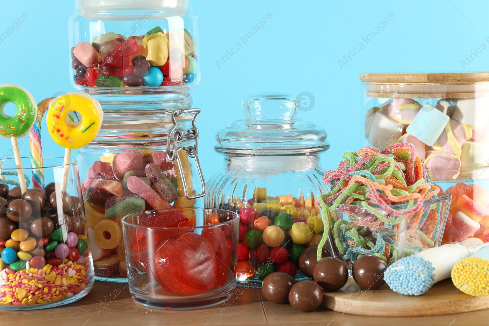 Photo of Candy bar. Many different sweets on wooden table against light blue background, closeup