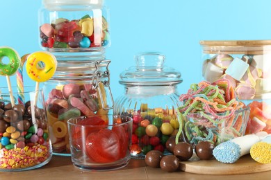 Candy bar. Many different sweets on wooden table against light blue background, closeup