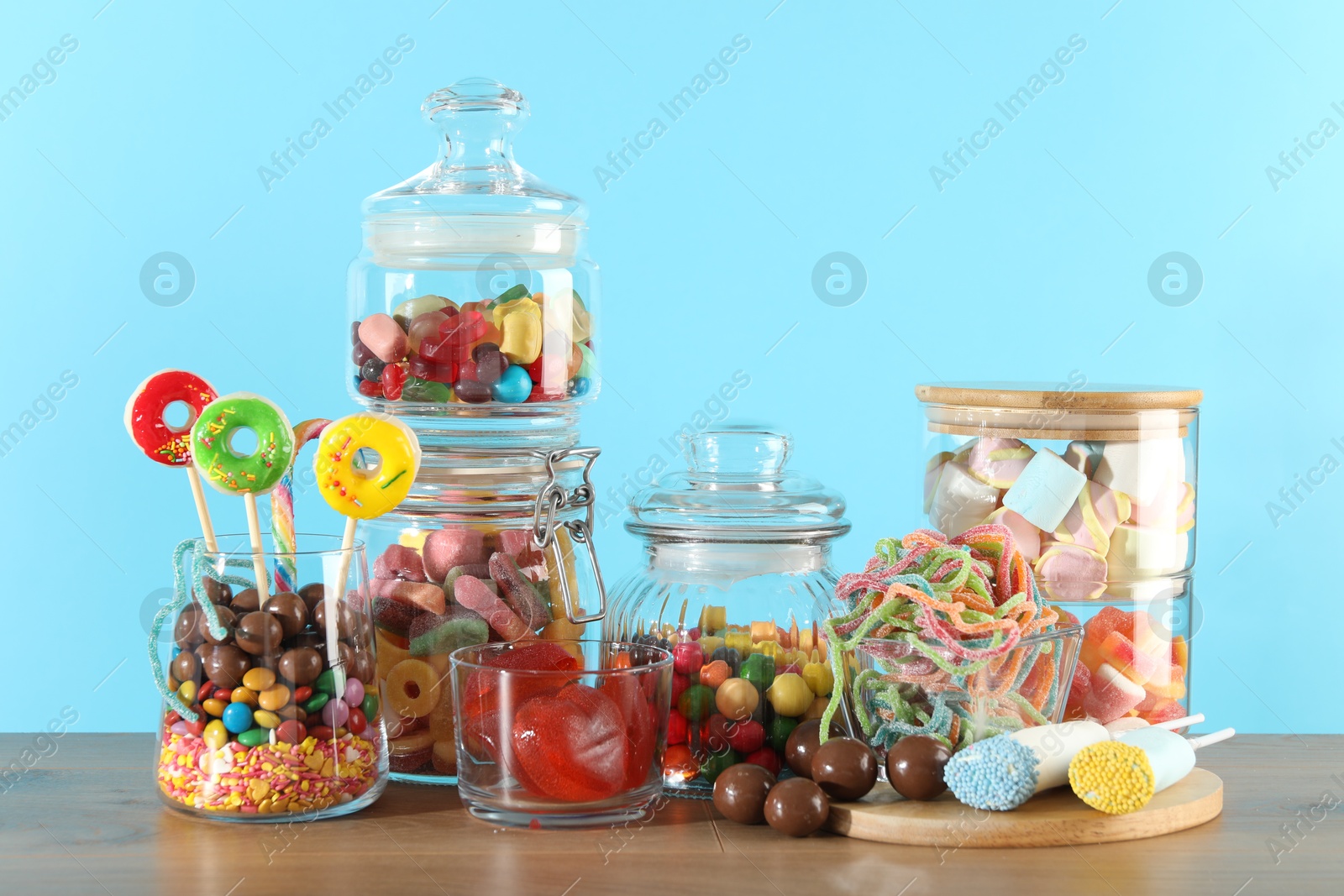 Photo of Candy bar. Many different sweets on wooden table against light blue background