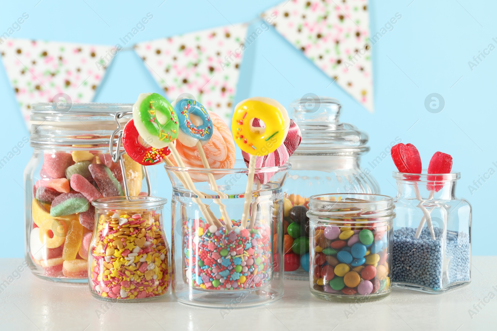 Photo of Candy bar. Many different sweets on white table against light blue background