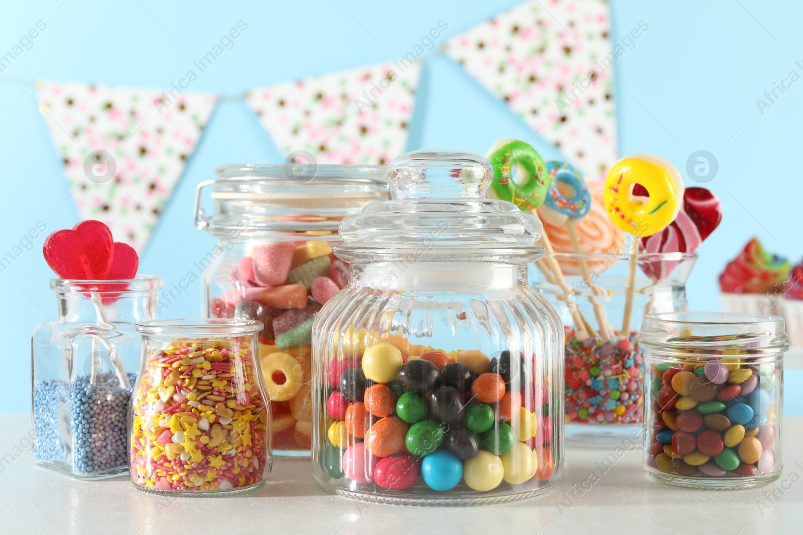 Photo of Candy bar. Many different sweets on white table against light blue background, closeup