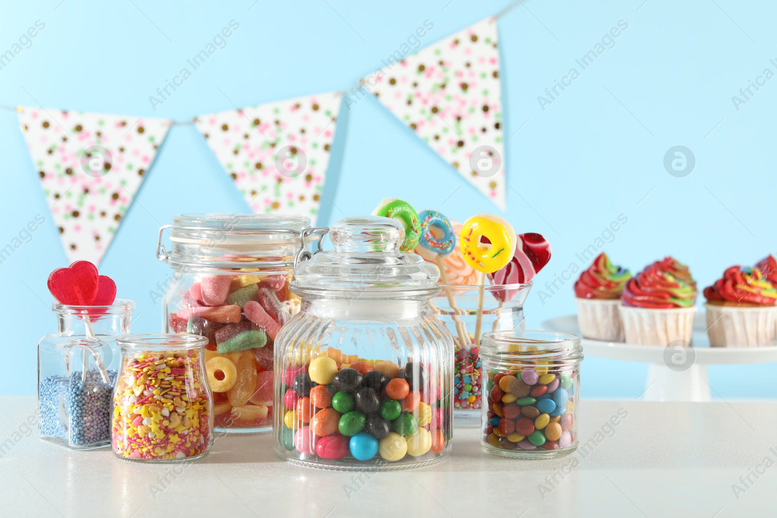 Photo of Candy bar. Many different sweets on white table against light blue background