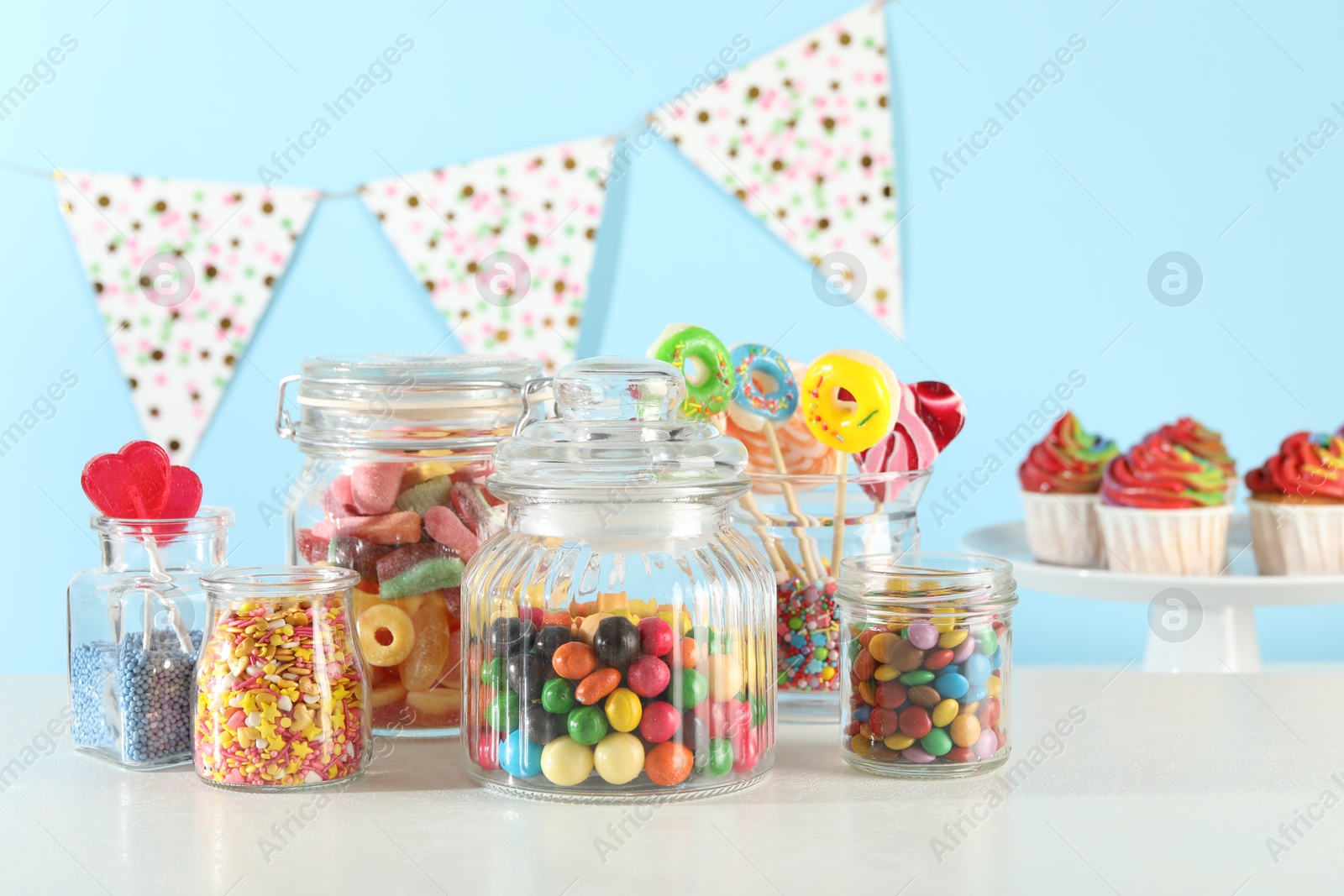 Photo of Candy bar. Many different sweets on white table against light blue background