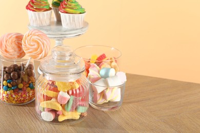 Photo of Candy bar. Many different sweets on wooden table against beige background, closeup. Space for text