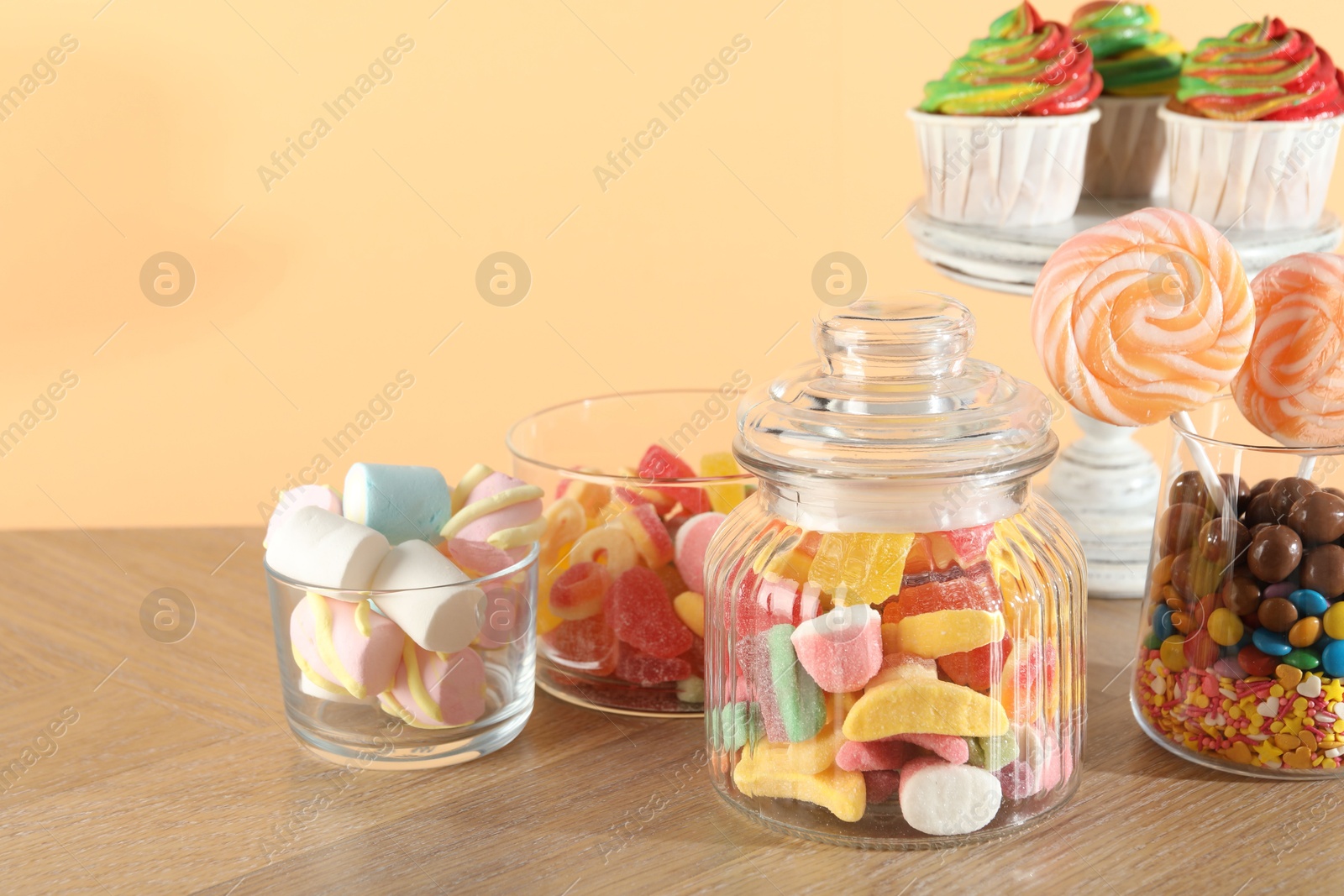 Photo of Candy bar. Many different sweets on wooden table against beige background, closeup. Space for text